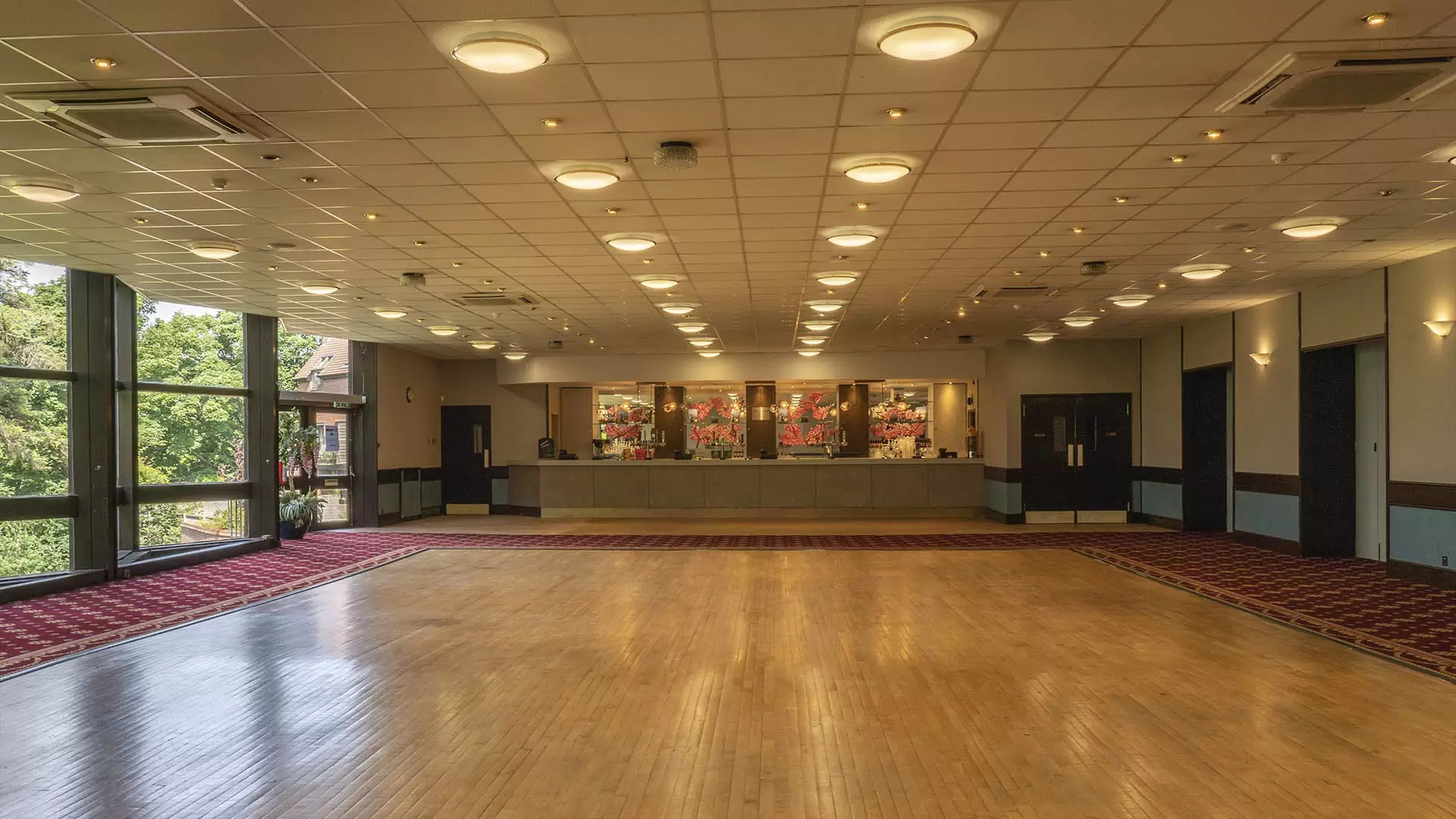 Spacious event venue with polished wooden floor, ideal for corporate meetings and gatherings.