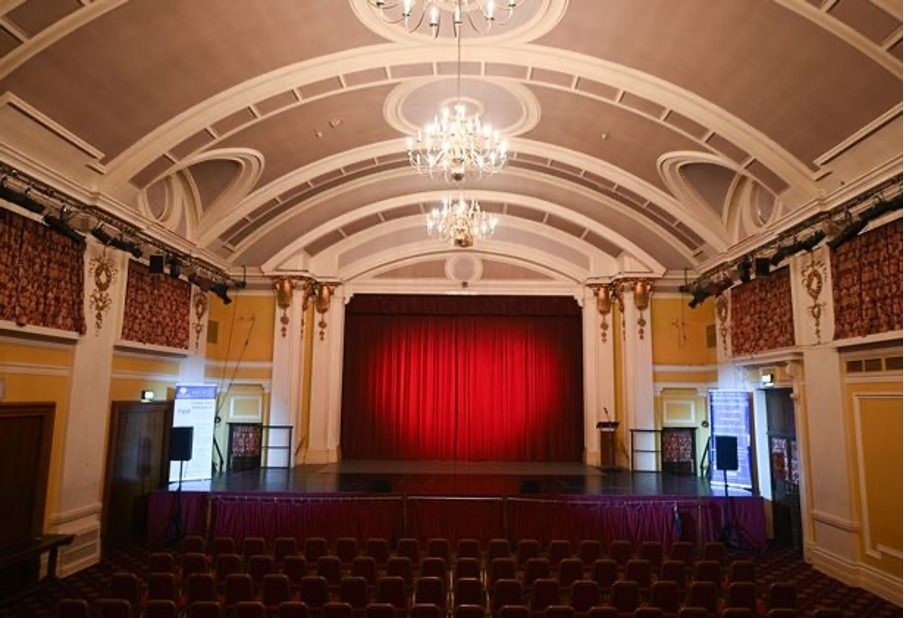 Elegant event space with red curtain stage, ideal for conferences and performances.