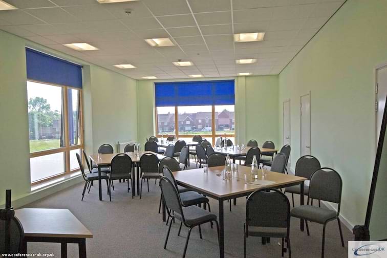 Versatile conference center with natural light, ideal for workshops and small conferences.