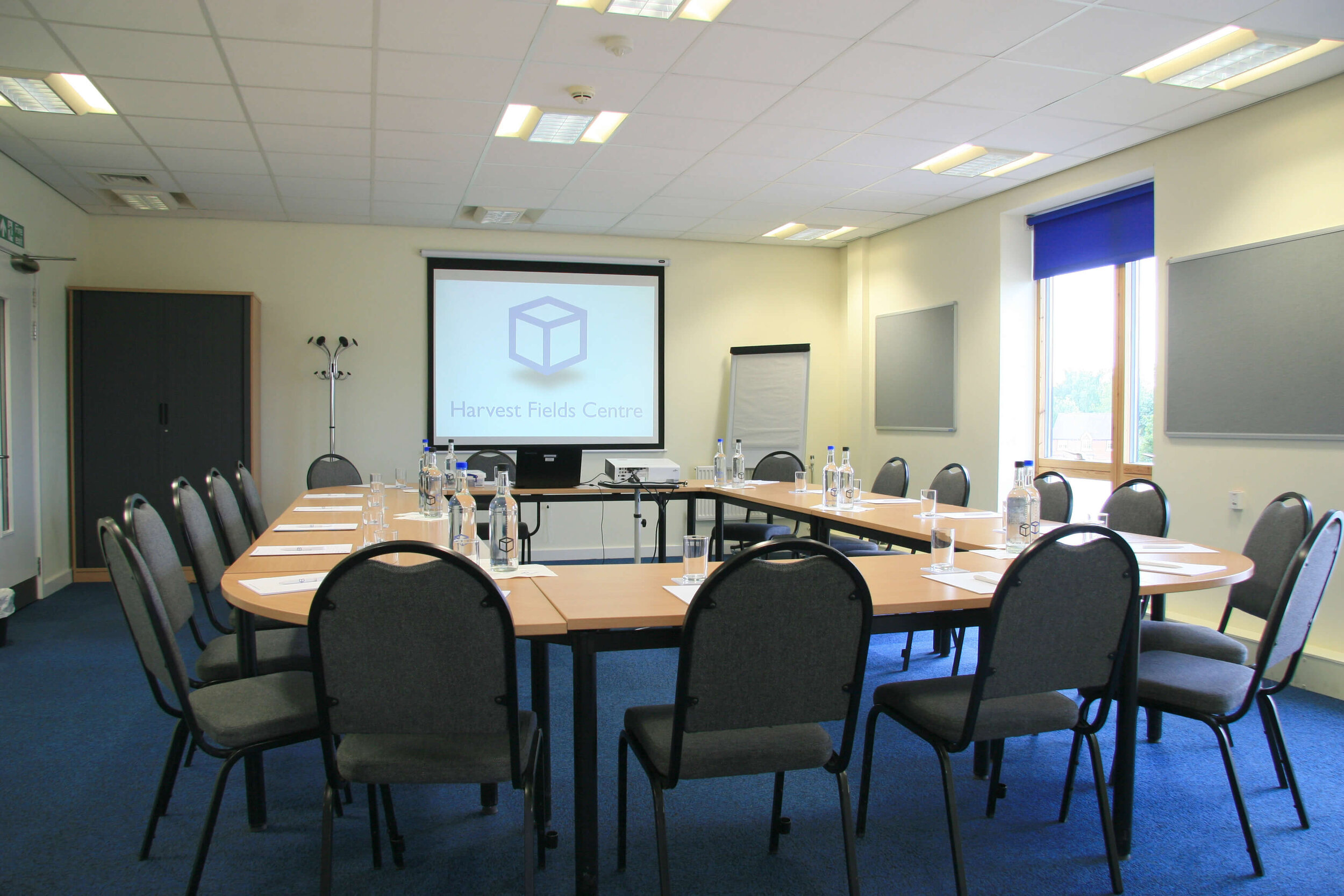 Meeting room setup with long table, projector screen for professional gatherings.