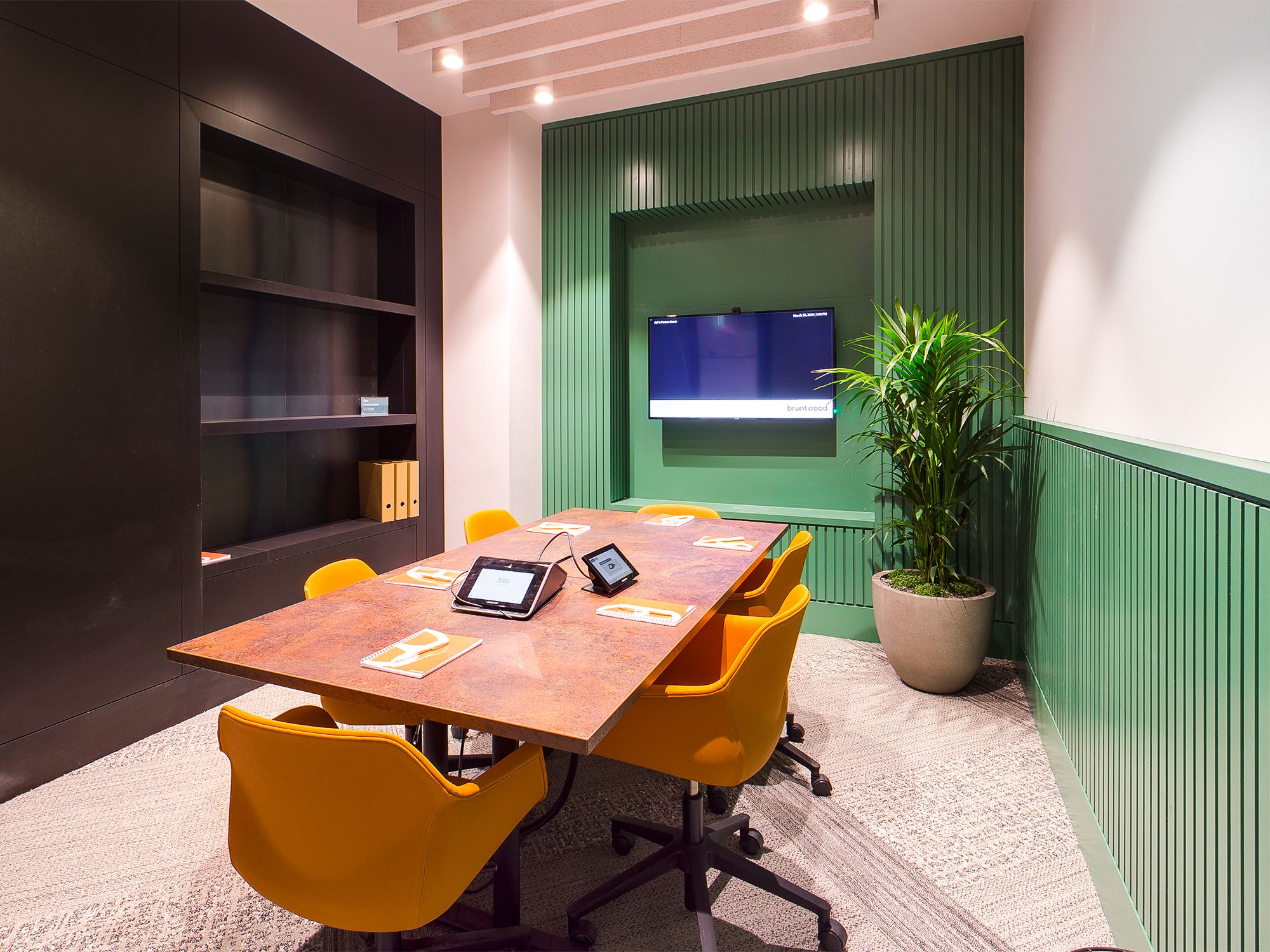 Modern meeting room with wooden table, orange chairs, ideal for team brainstorming sessions.