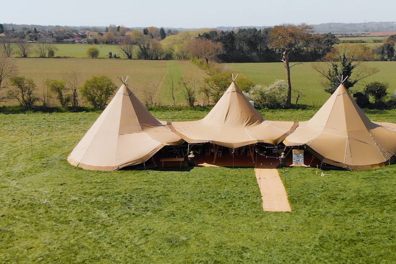 Spacious outdoor event venue with elegant tipis, perfect for weddings and festivals.