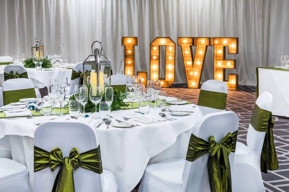 Function room at Village Hotel Solihull, elegant wedding setup with "LOVE" sign.