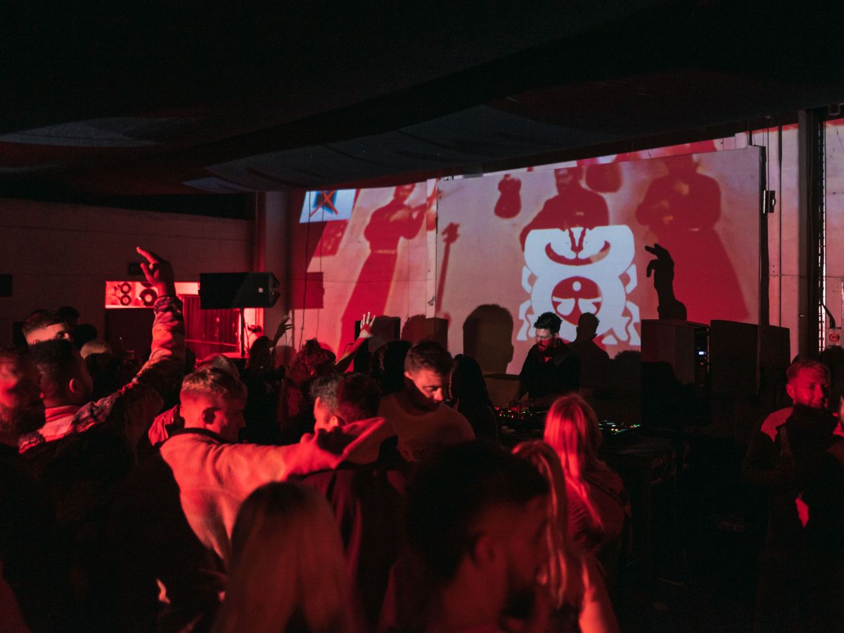 Vibrant warehouse event with attendees dancing to live music and dynamic lighting.