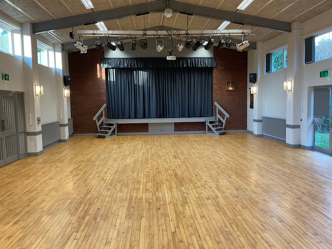 Small hall in Dodford Village Hall with polished wooden floor, ideal for events and gatherings.