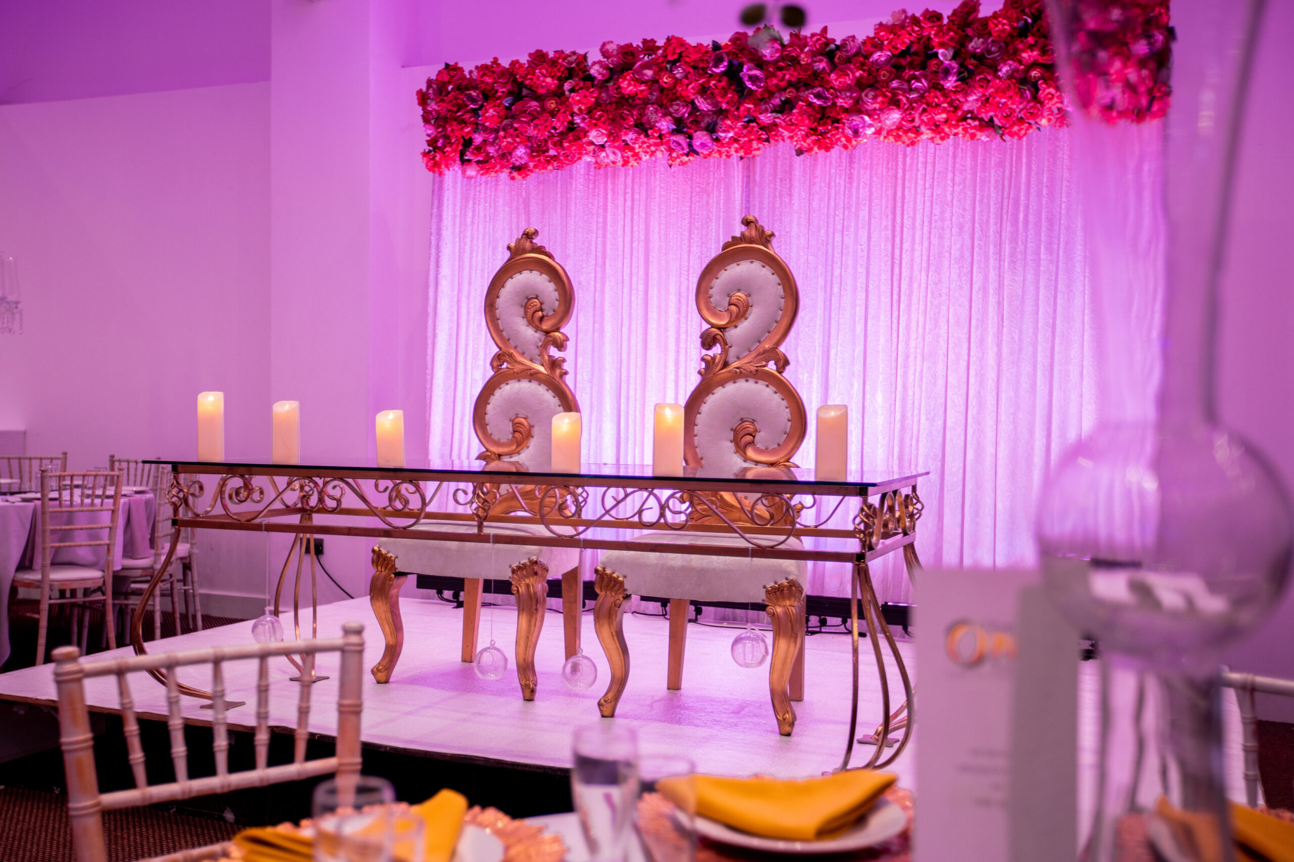 Elegant event space with floral stage and luxurious table for formal gatherings.