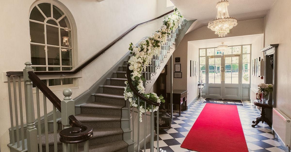 Elegant entrance with grand staircase in Warwick House, perfect for weddings and events.