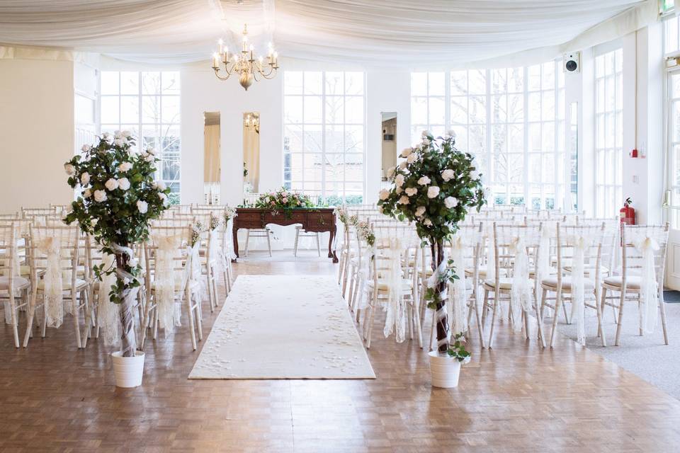 Ornate wedding venue with elegant white chairs and floral arrangements in Warwick House.