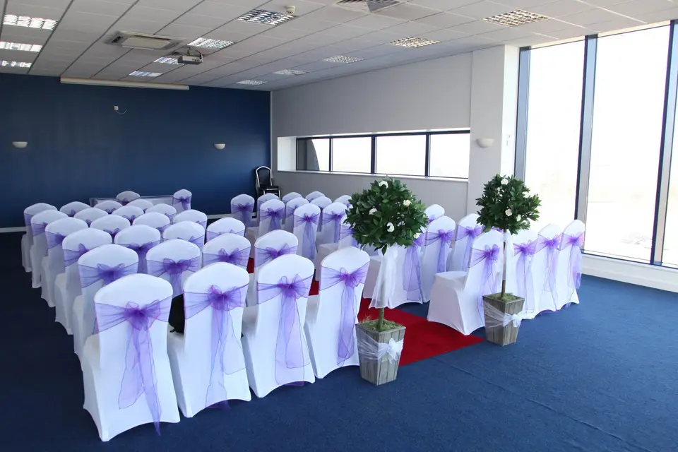 Gala Dinner Hall at Sixways Stadium with white chairs and lavender sashes for events.