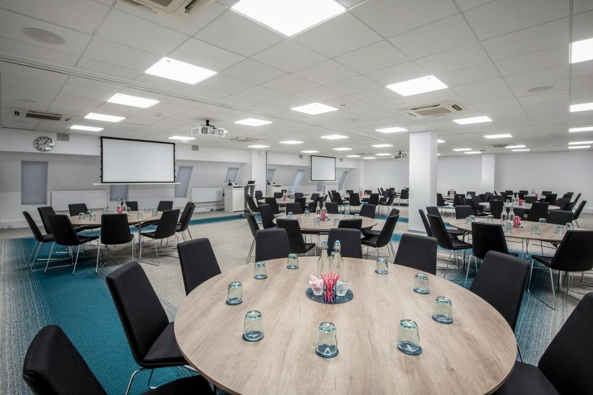 Versatile business center with round tables, ideal for conferences and networking events.