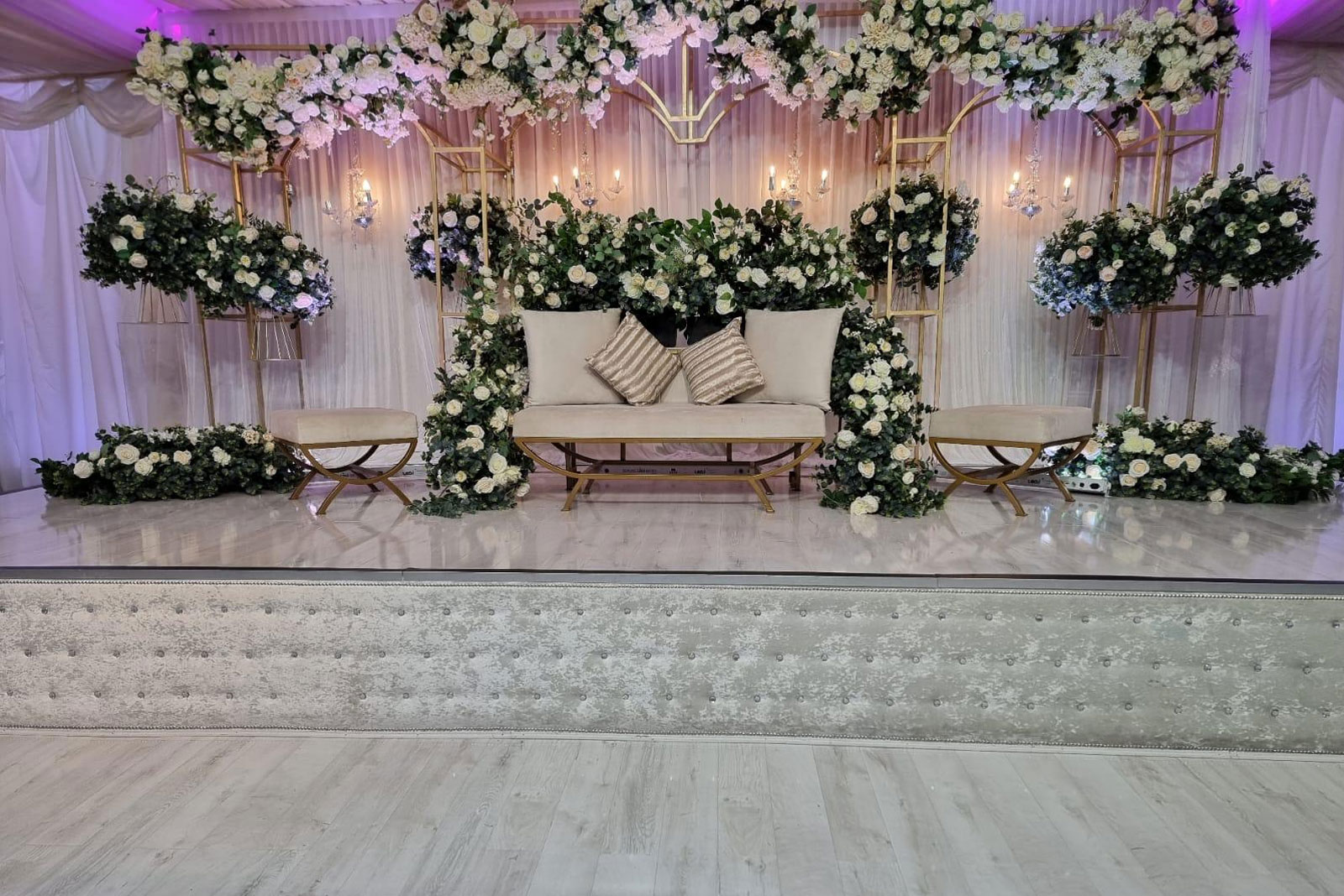 Elegant event stage with floral backdrop in Digbeth Hall for weddings and upscale gatherings.