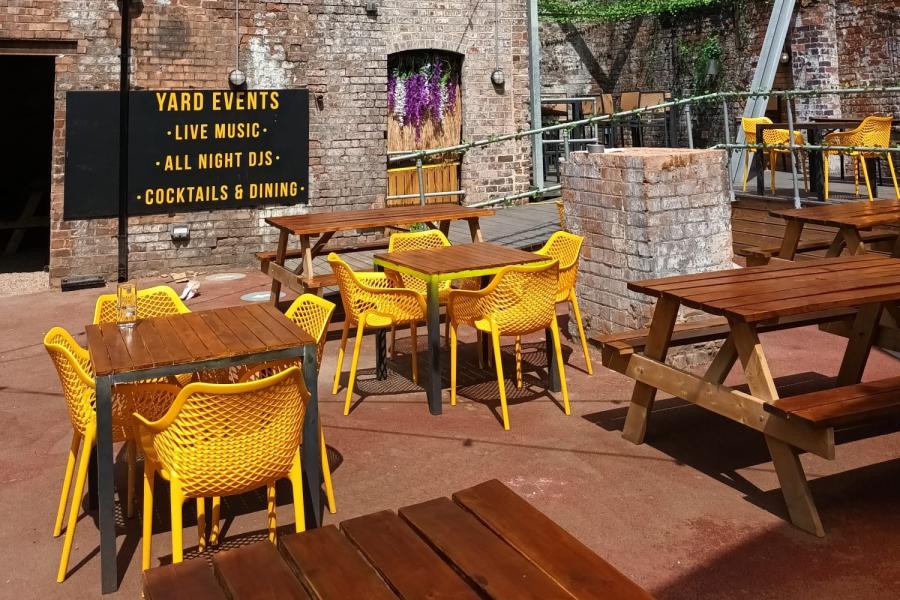 Vibrant outdoor event space with yellow furniture, ideal for live music and cocktail receptions.
