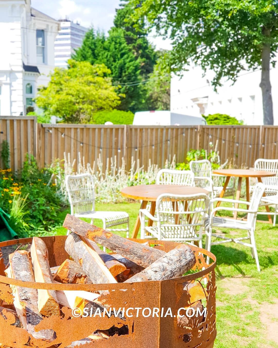 Charming outdoor event space with rustic seating and fire pit for summer gatherings.