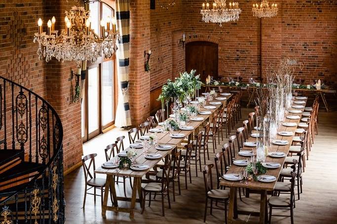 Elegant barn event space with wooden tables, ideal for weddings and upscale gatherings.
