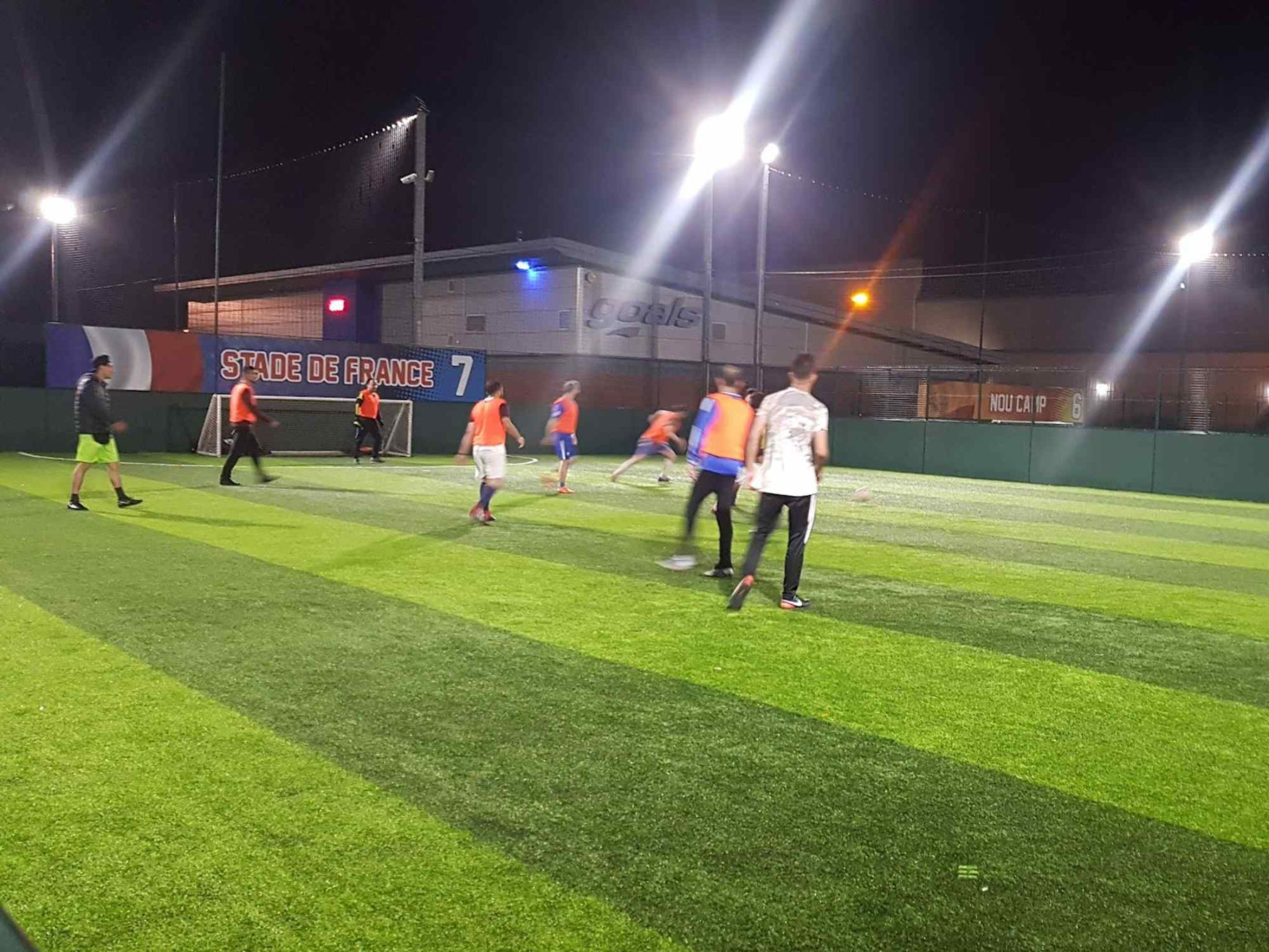 Evening soccer match on vibrant artificial turf at Rowley Campus for team-building events.