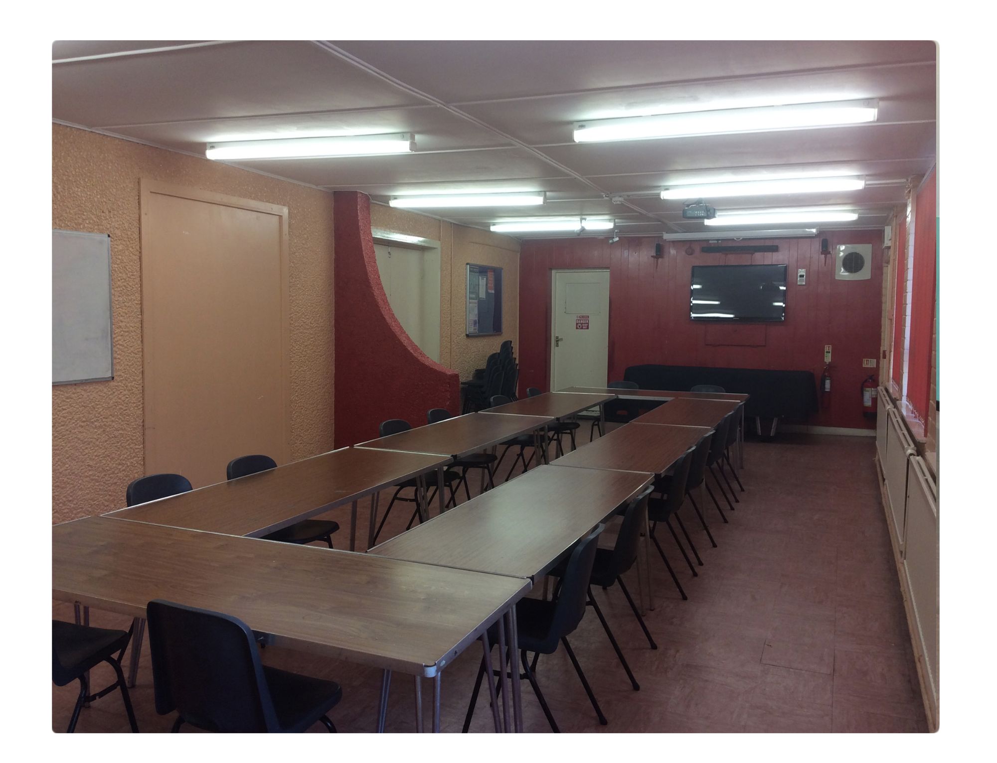 Versatile meeting room with long tables, ideal for workshops and team meetings.
