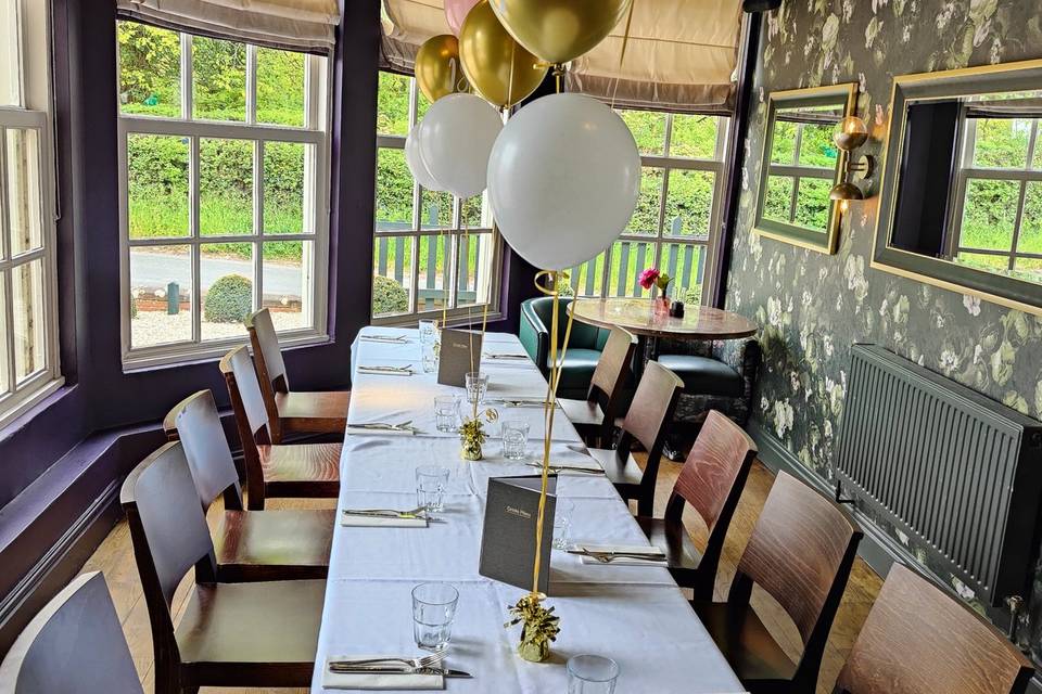 Elegant dining table with balloons in The Lyttelton Arms courtyard for celebrations.