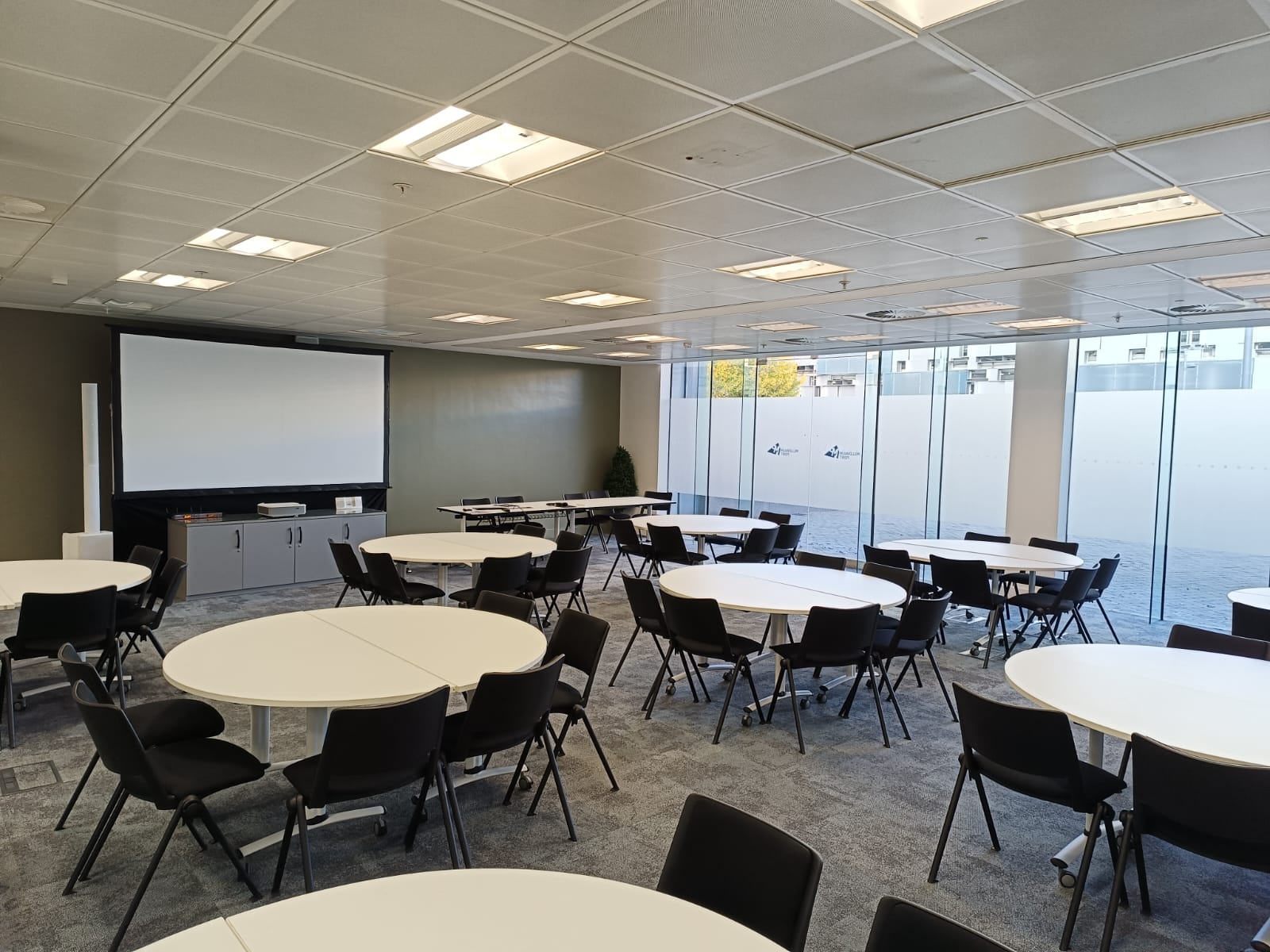 Versatile training room with round tables, ideal for meetings and events at Nishkam Centre.