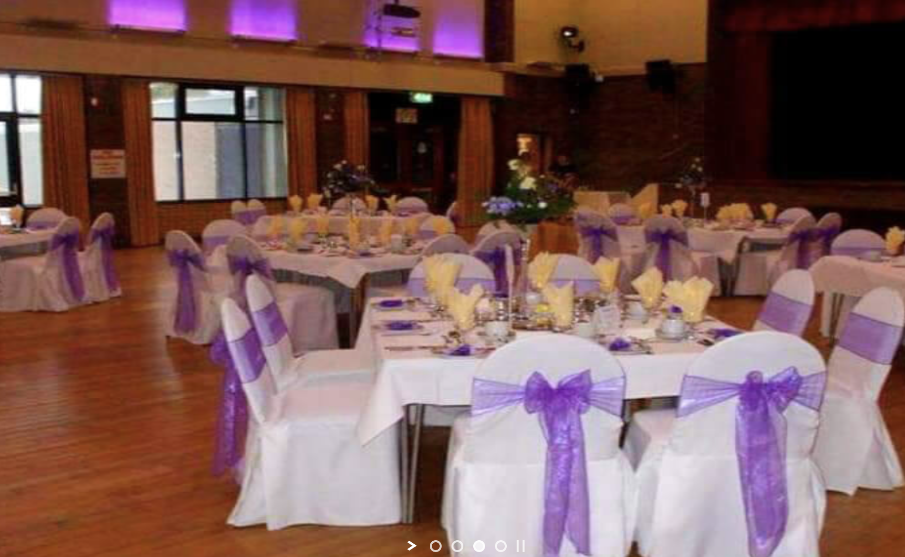 Elegant event space at The Addison Centre with white tables and purple sashes for weddings.