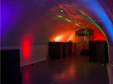 Versatile event space with curved ceiling and dynamic lighting for corporate and social gatherings.