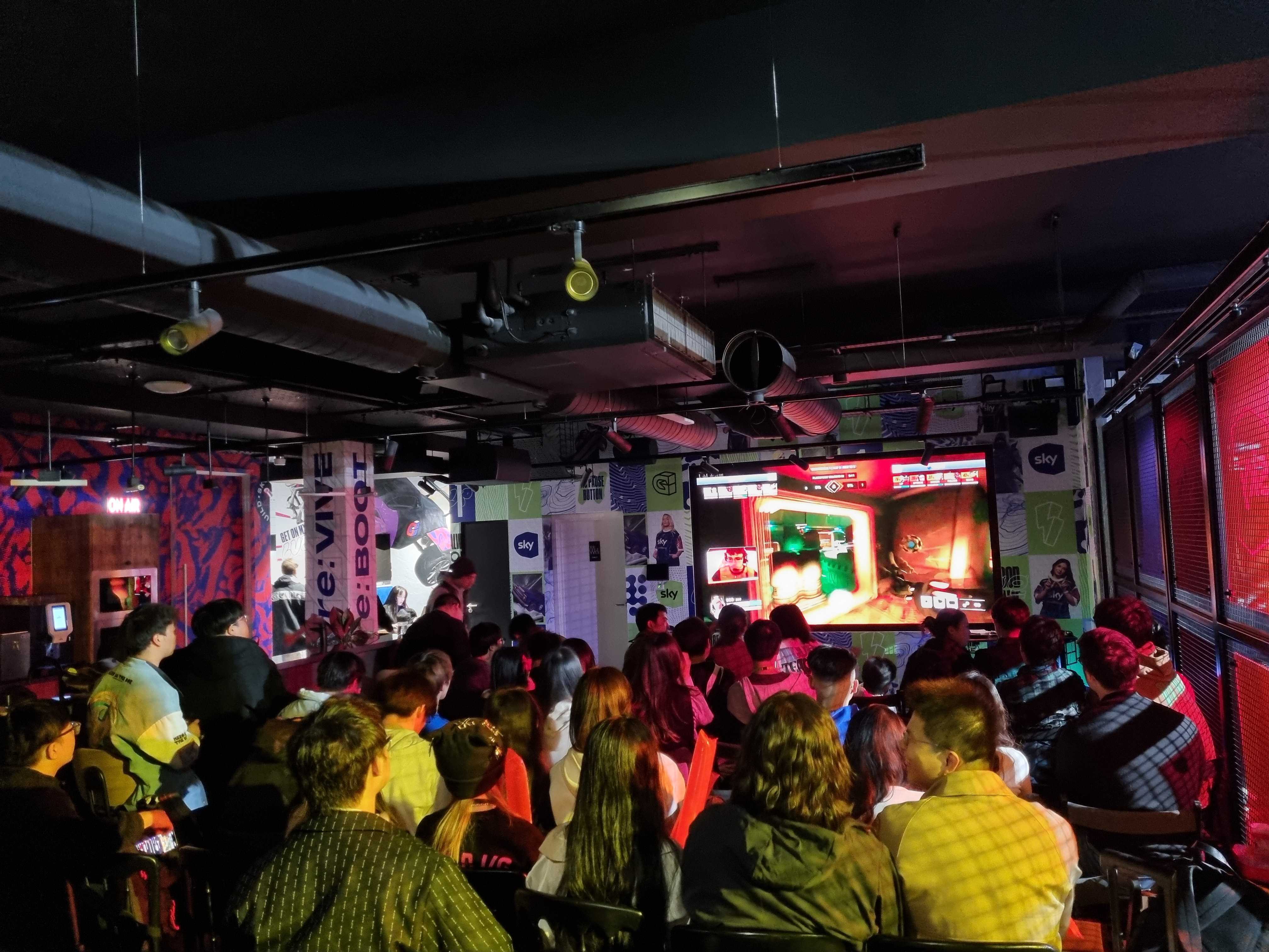 Vibrant gaming event at Sky Guild with engaged audience and large screen presentation.