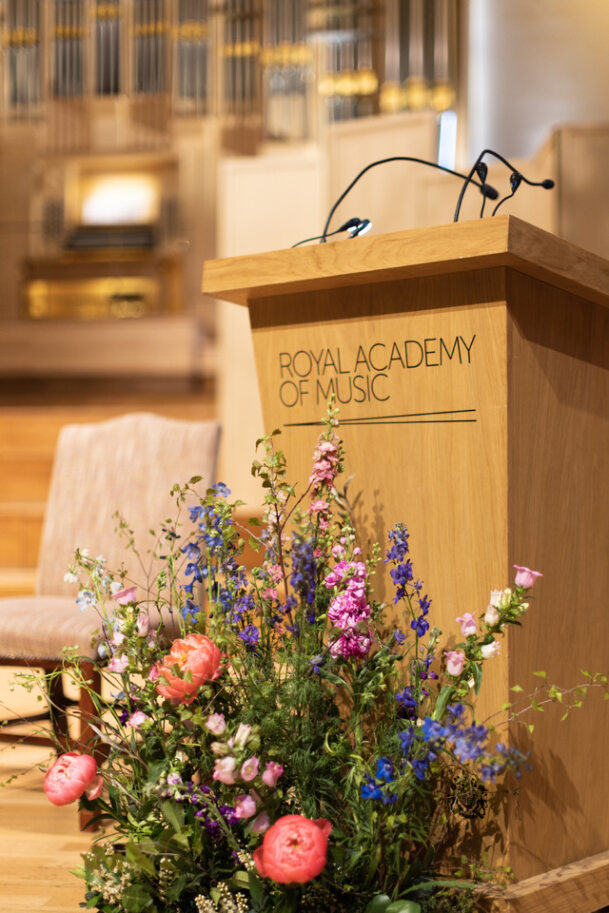 Duke's Hall podium with floral display for elegant music performances and lectures.