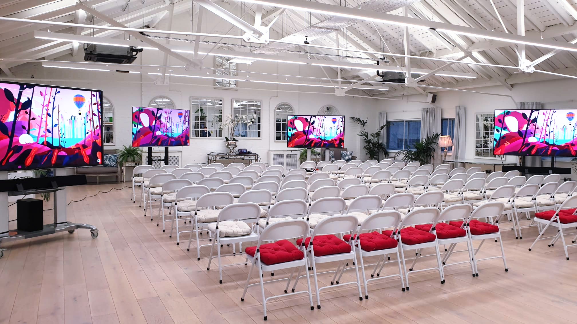Event space with white chairs and red cushions, perfect for presentations or workshops.