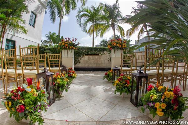 Patio Del Fauno wedding venue with gold chairs and vibrant floral arrangements.