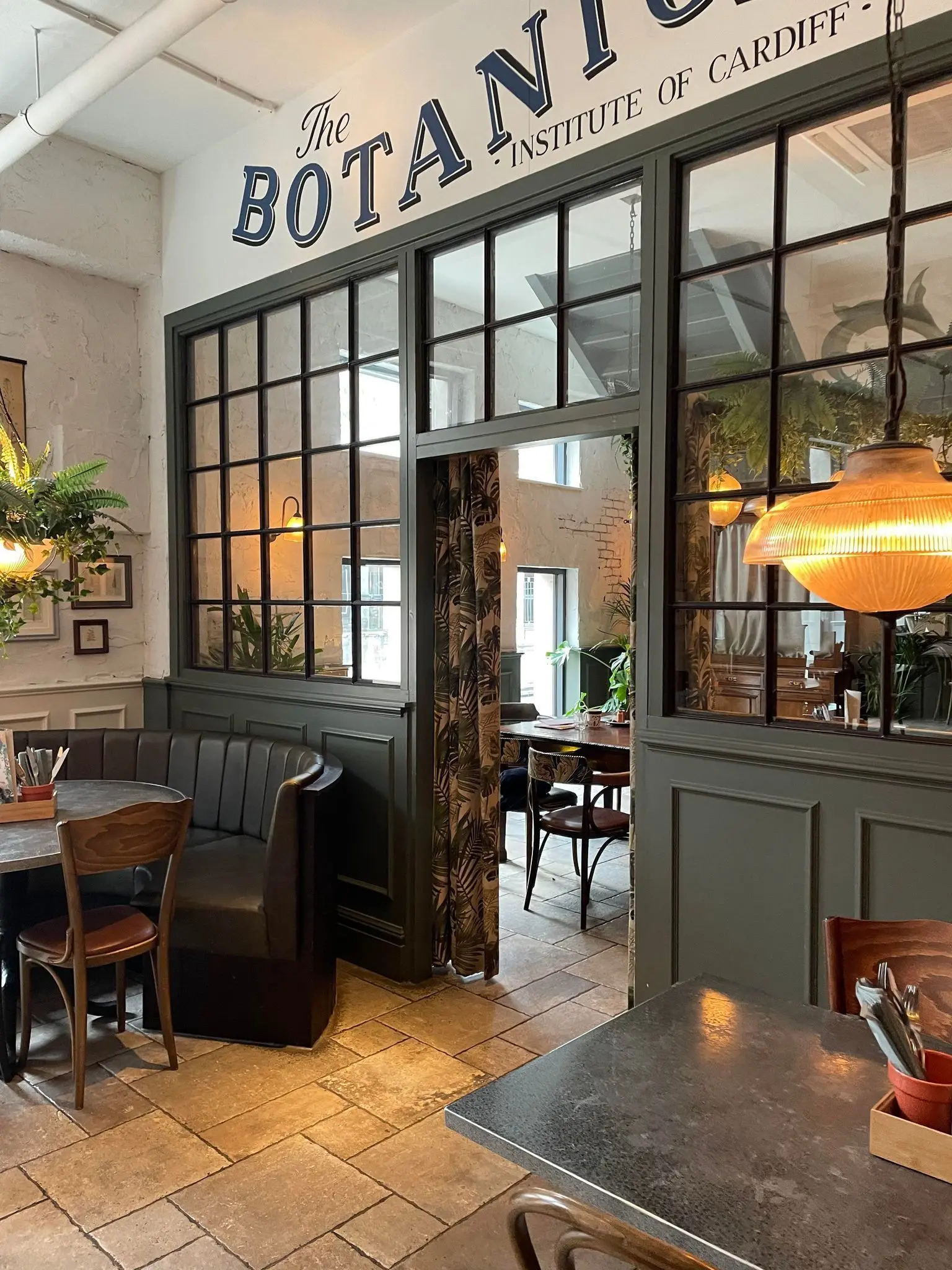Modern dining space at The Botanist Cardiff with large windows, ideal for gatherings.