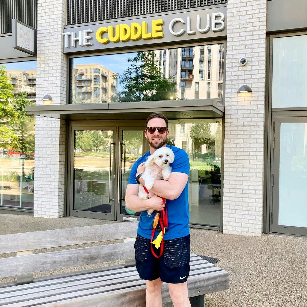 Professional holding small dog outside modern event venue for pet-friendly gatherings.