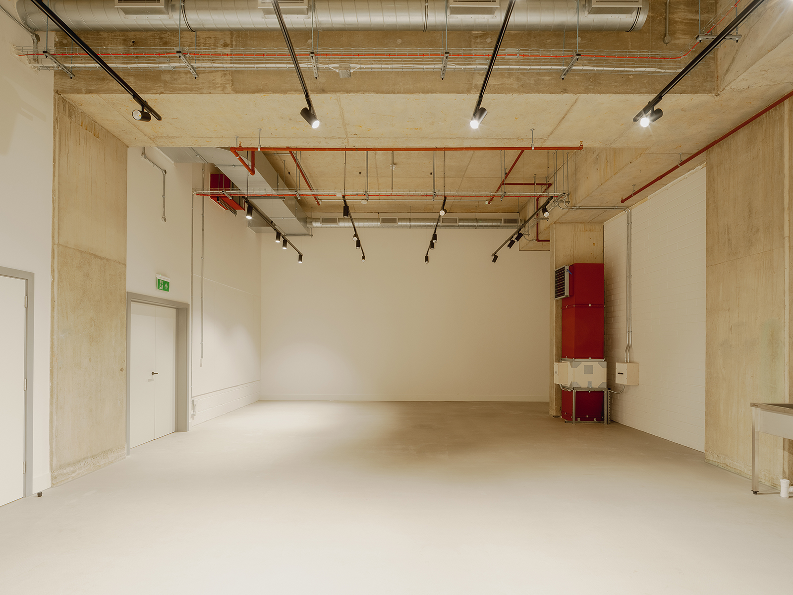 Versatile auditorium with concrete walls, ideal for meetings and workshops.