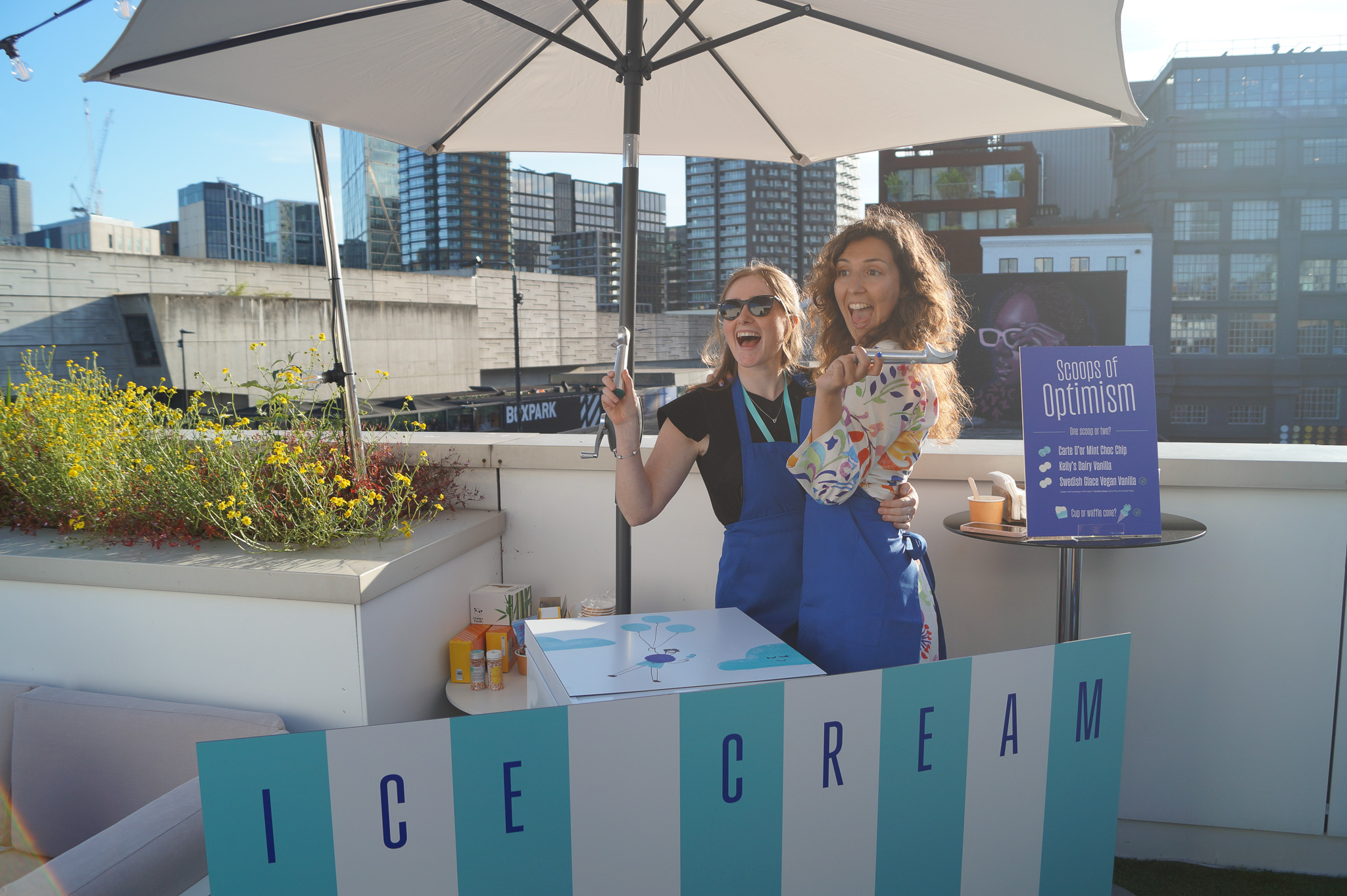 Vibrant outdoor event at Sky Guild Gaming Centre with ice cream station and city skyline.