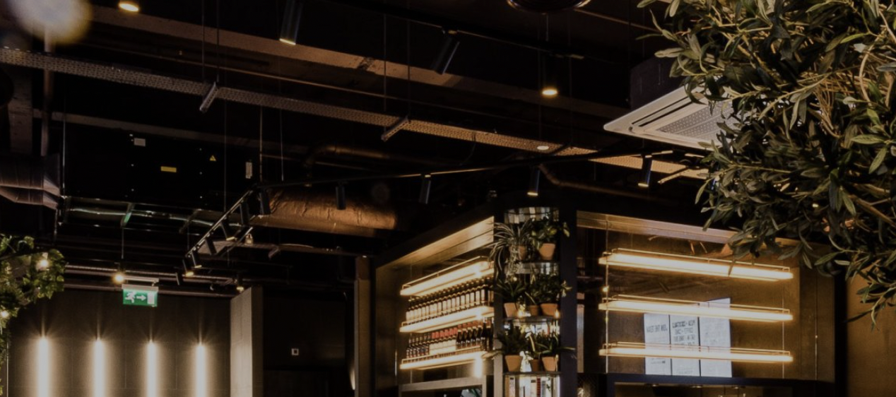 Modern industrial venue in PizzaLuxe Manchester for events, featuring warm lighting and greenery.