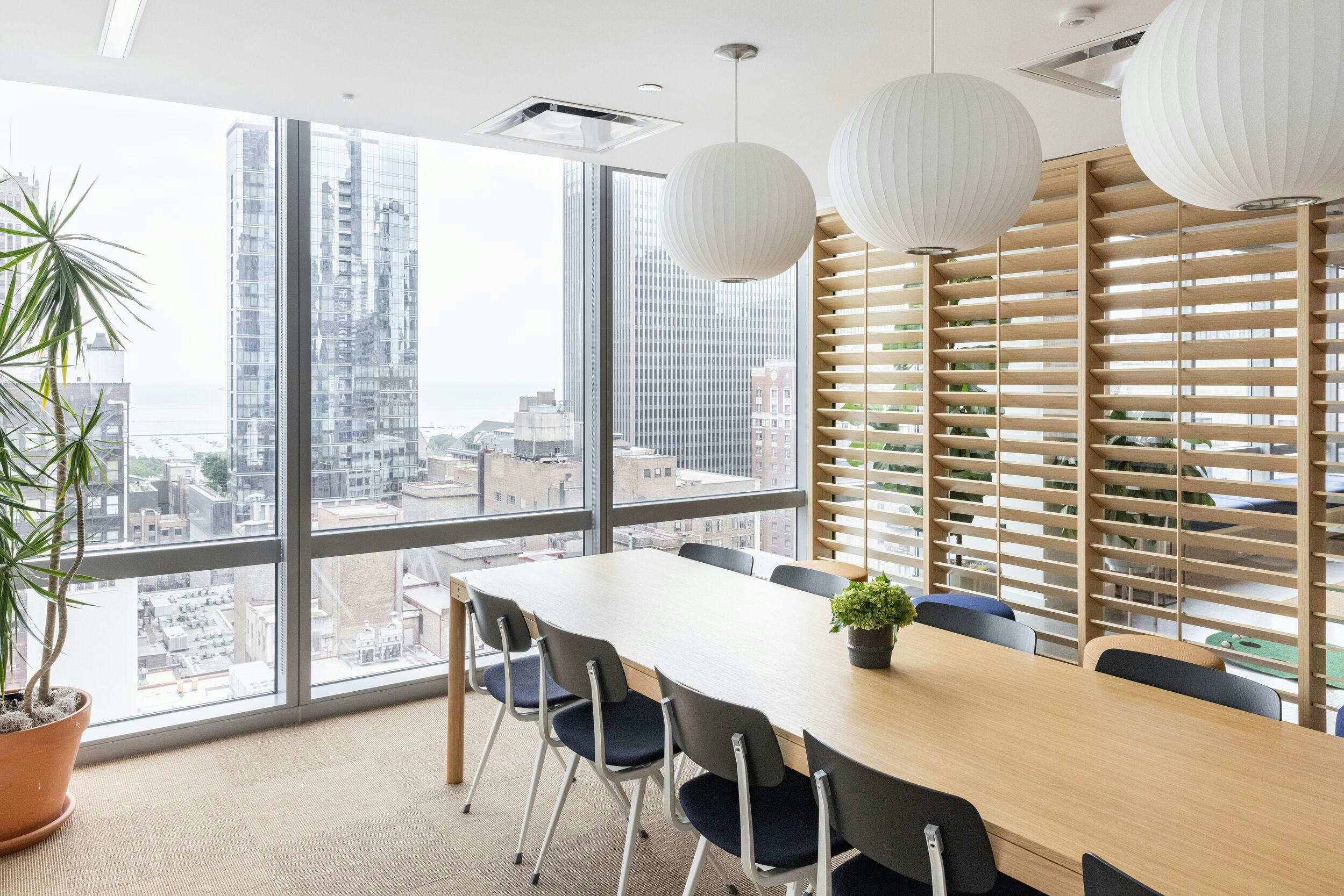 Modern WeWork meeting room with large wooden table, ideal for workshops and meetings.