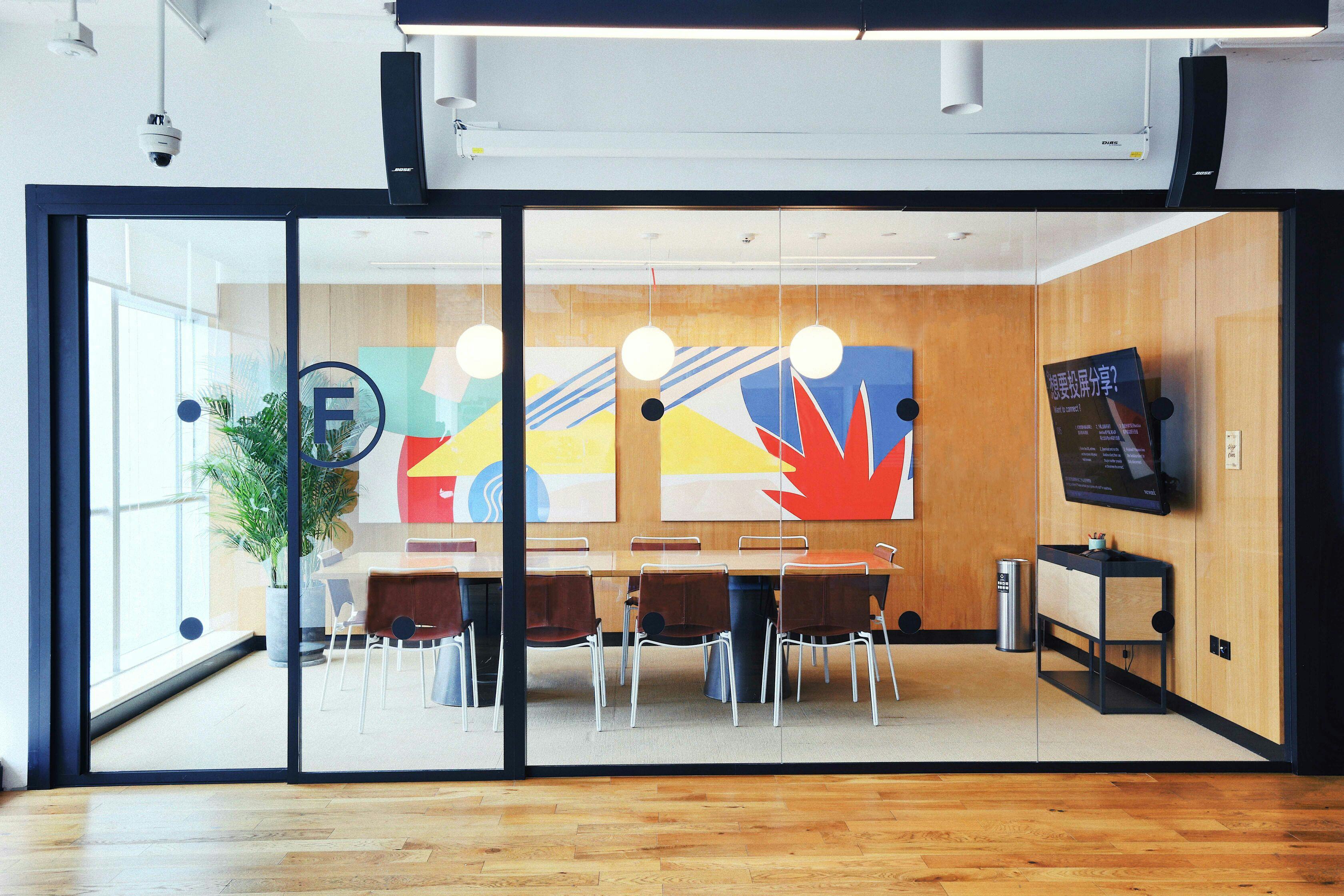 Modern WeWork meeting room with glass walls, ideal for collaborative events and presentations.