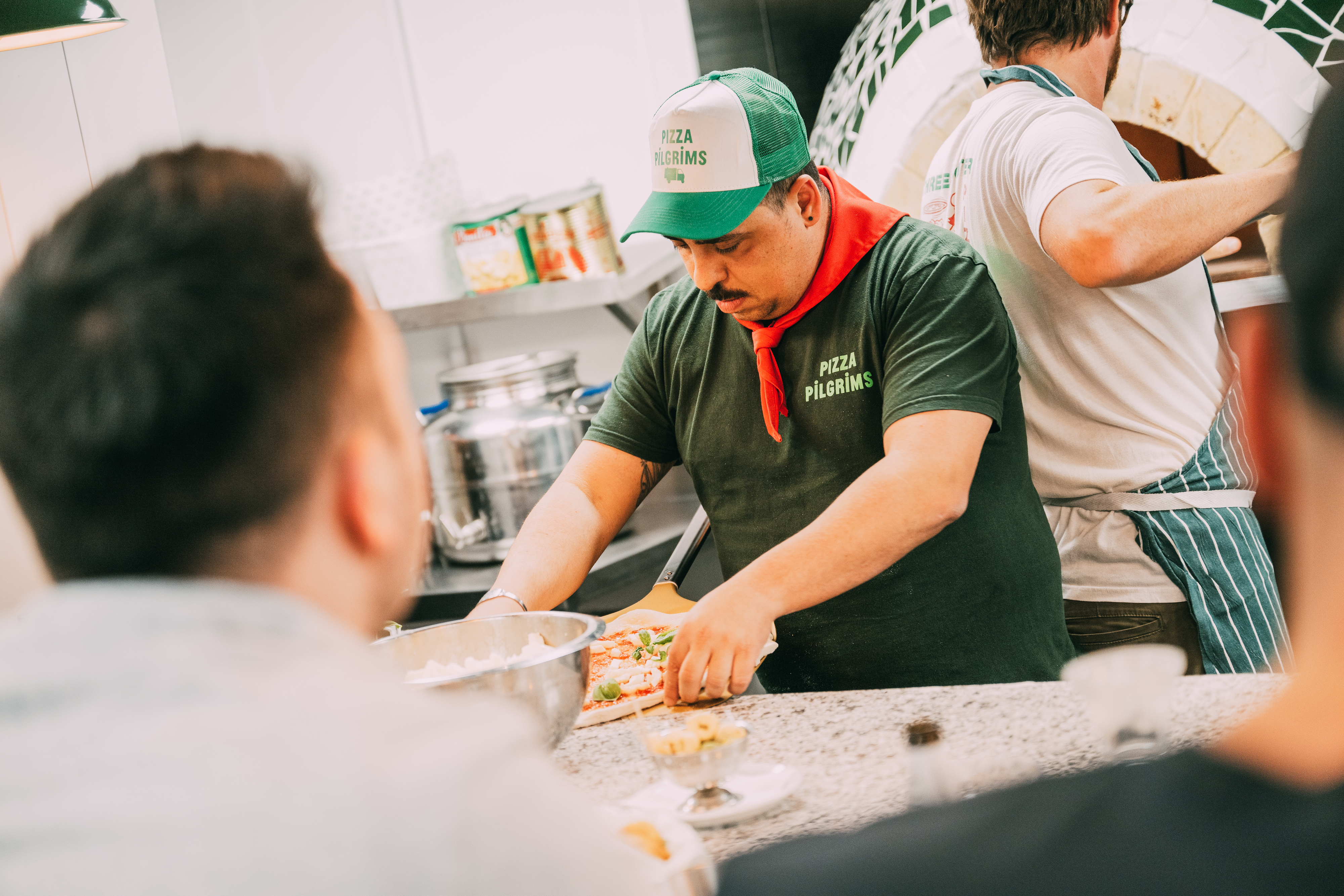 Chef preparing pizza in vibrant kitchen for team-building culinary event.