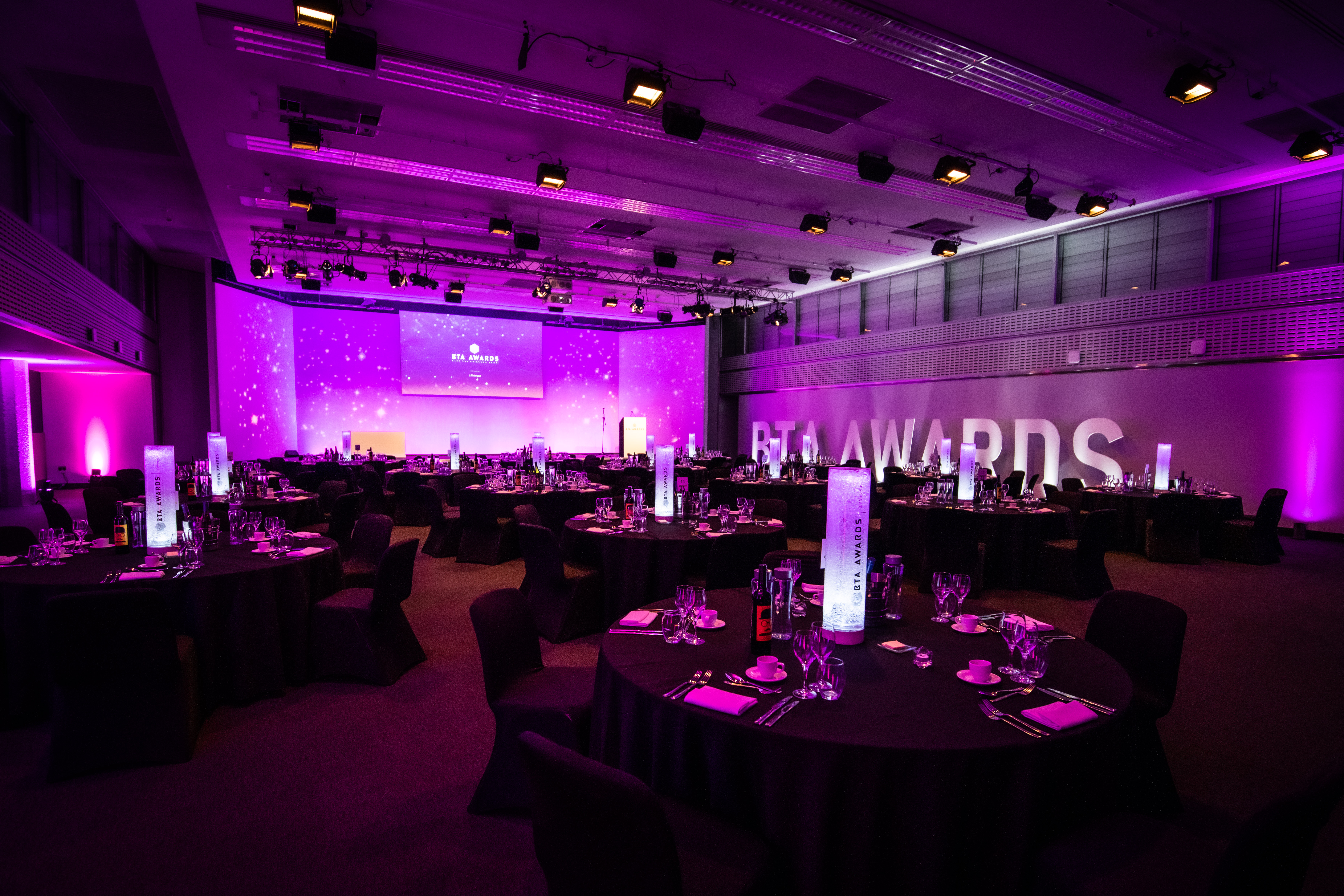 Elegant awards ceremony setup at Mountbatten, featuring round tables and purple lighting.