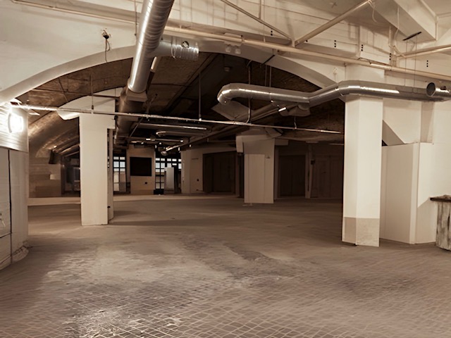 Spacious industrial venue with high ceilings for corporate events and social gatherings.