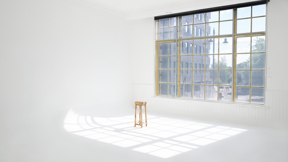 Bright minimalist studio with natural light, ideal for workshops and meetings.