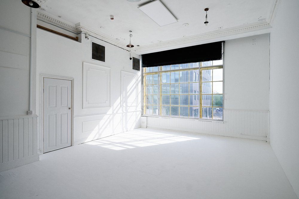 Bright minimalist event space with large window, perfect for meetings and workshops.