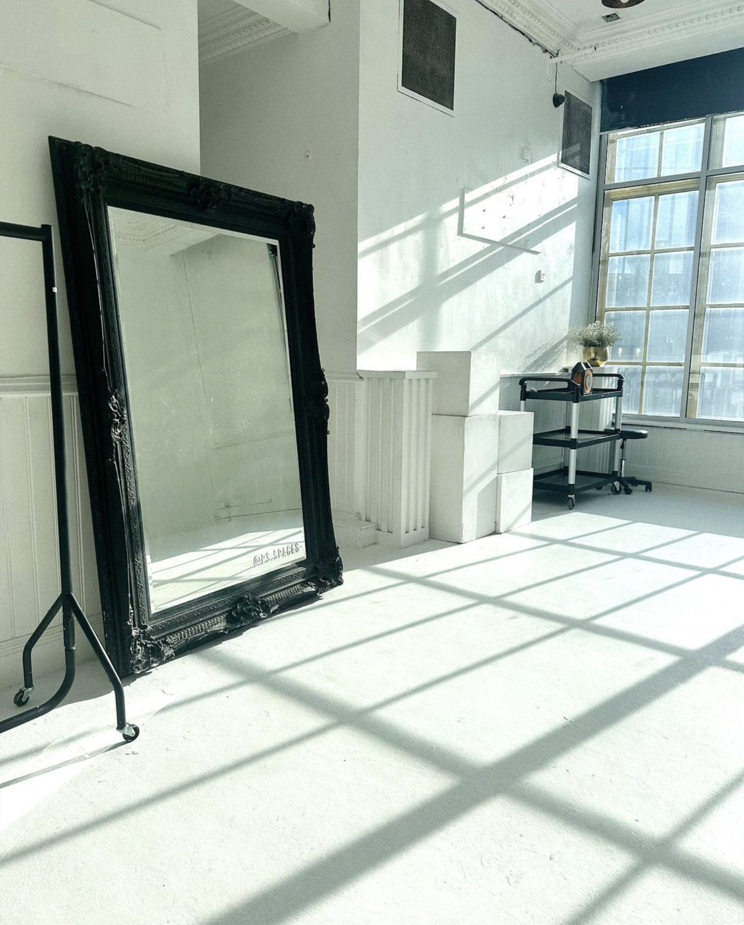 Bright minimalist event space with large mirror, perfect for gatherings and workshops.