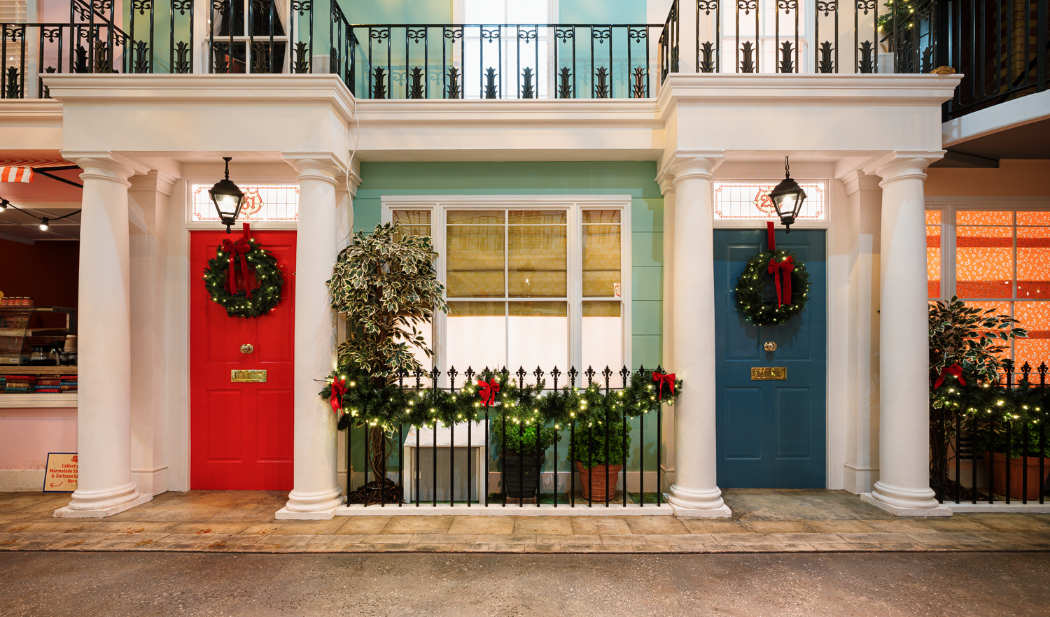 Christmas party entrance with colorful doors and festive wreaths at Paddington Bear Experience.
