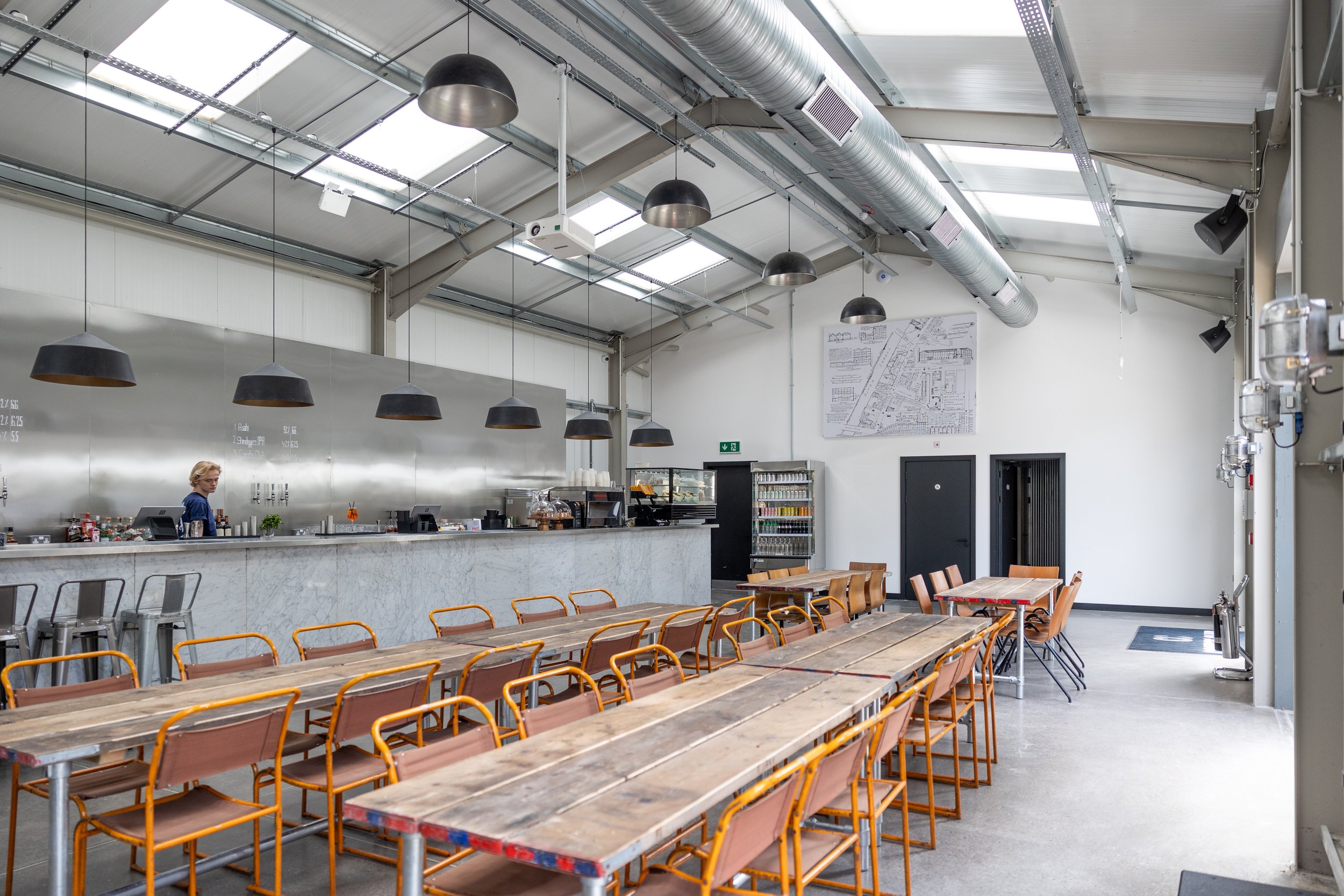 Spacious industrial venue with communal tables for workshops and networking events.