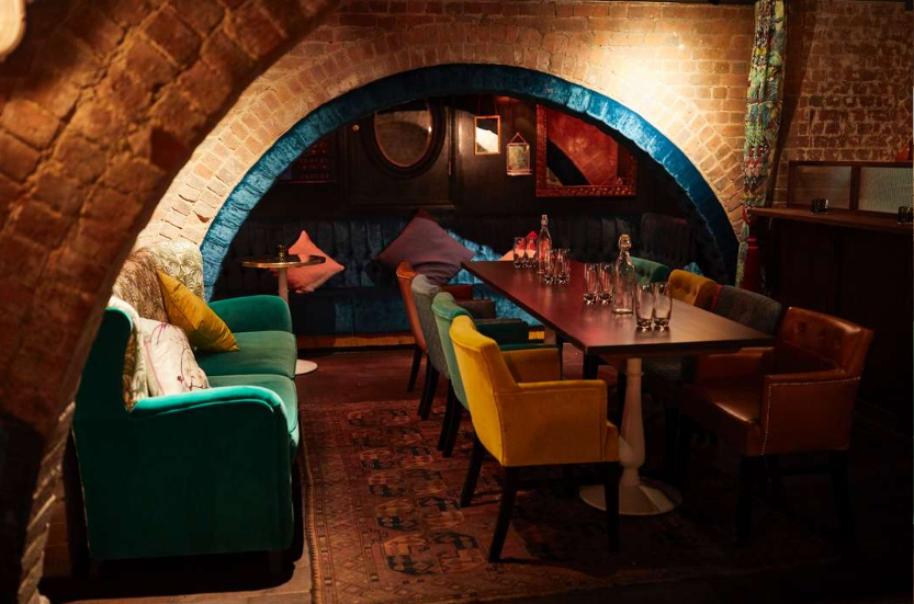 Cozy Firefly Cellar Bar with arched brick wall, ideal for meetings and workshops.