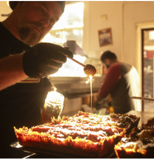 Culinary professional drizzling honey in The Space at Parts & Labor for event catering.