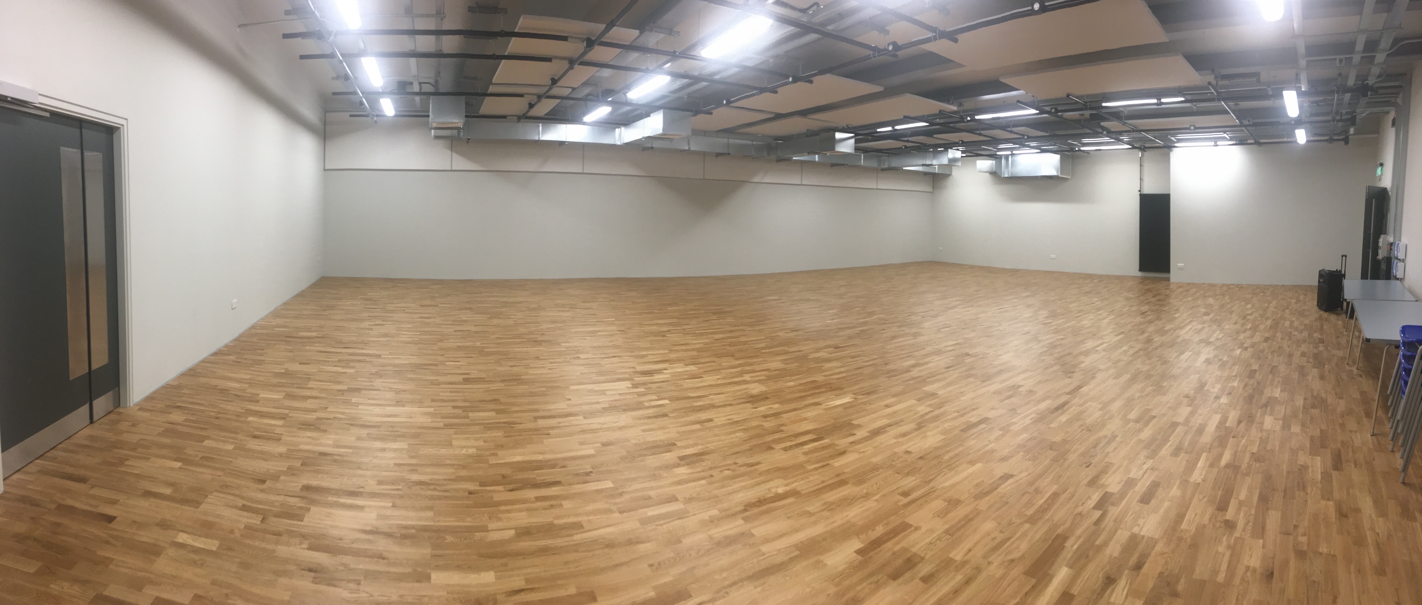 Spacious rehearsal studio with polished wood floors, ideal for meetings and workshops.
