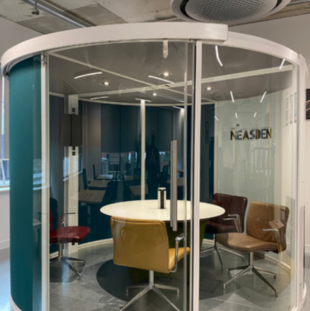 Modern meeting pod with glass walls for collaborative brainstorming in Neasden workspace.