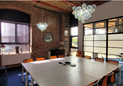 Modern conference room with large table, exposed brick, ideal for meetings and collaboration.