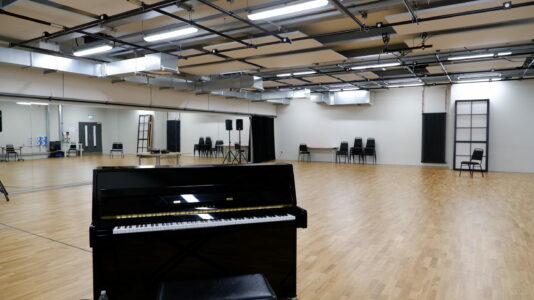 Spacious rehearsal suite with wooden floor, ideal for meetings and workshops.