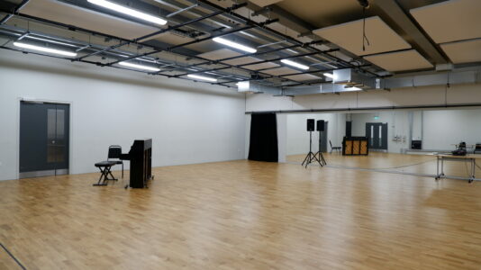 Versatile rehearsal suite with polished wooden floor for meetings and performances.